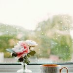 A relaxing scene with a 'magnificent mum' mug and flowers by a rainy window.